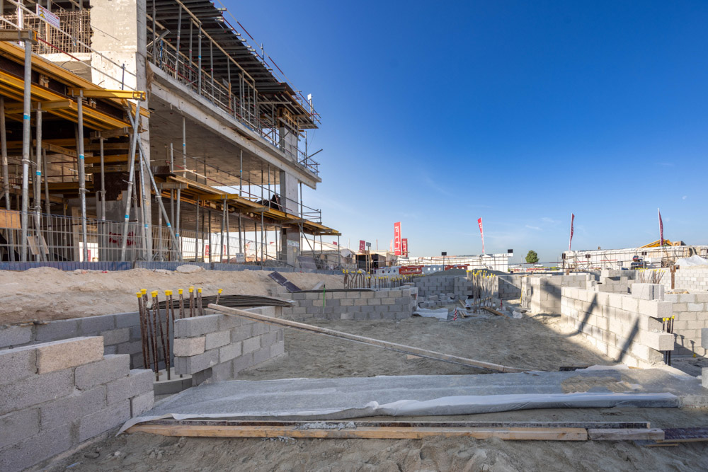 Cotier House 2 By Imtiaz Construction site with scaffolding, concrete blocks, and equipment under a clear blue sky.